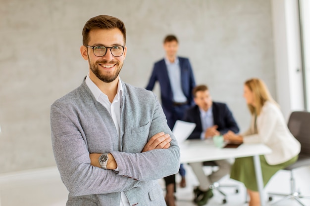 Hombre de negocios joven hermoso que confía en la oficina delante de su equipo