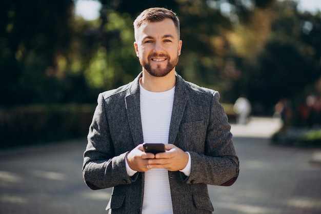 Hombre de negocios joven hermoso que usa el teléfono fuera de la calle