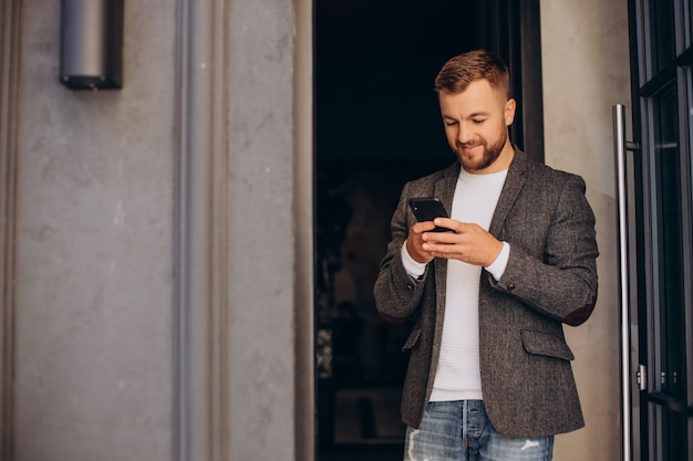 Hombre de negocios joven hermoso que usa el teléfono fuera de la calle