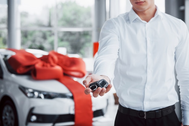 Hombre de negocios joven con llaves en sus manos, compra un coche en la cabina.