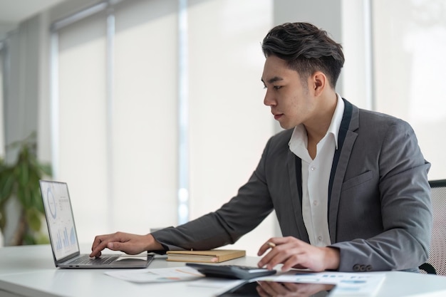 Hombre de negocios joven mira la pantalla de la computadora portátil calcular gastos gastos pagar facturas impuestos en línea hombre ocupado administrar el presupuesto de la empresa encargarse del papeleo financiero