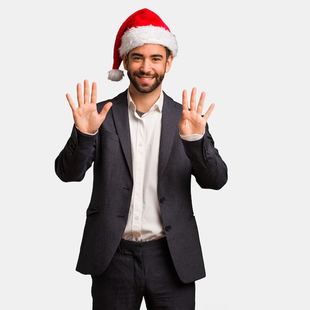 Hombre de negocios joven que lleva el sombrero de santa que muestra el número nueve