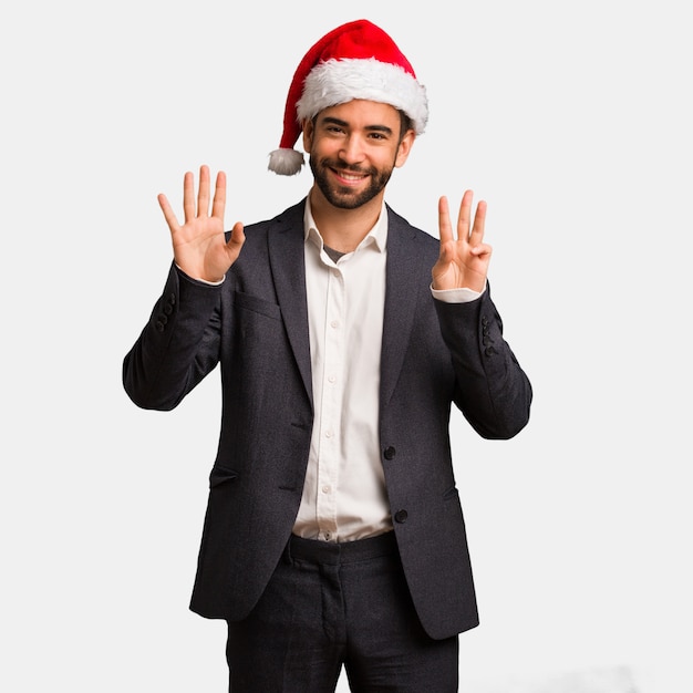 Hombre de negocios joven que lleva el sombrero de santa que muestra el número ocho