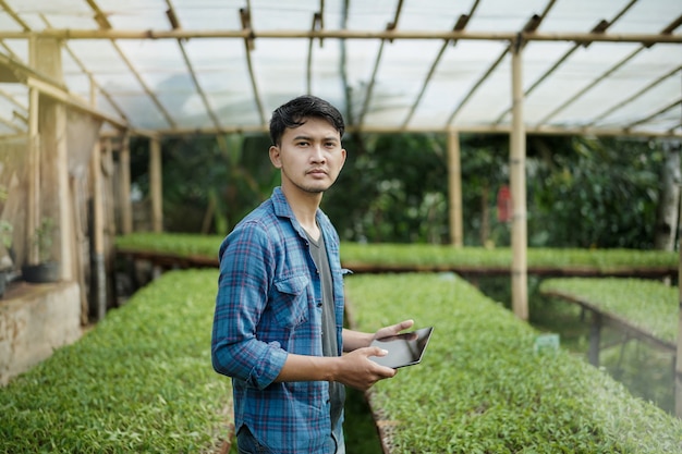 Hombre de negocios joven que usa una tableta que controla el concepto de la foto de la agricultura digital de la granja