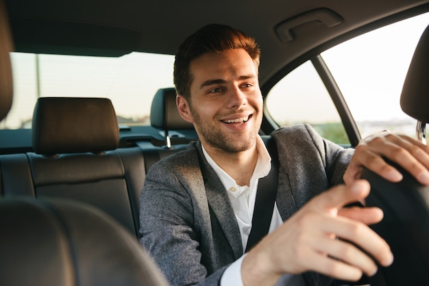 Hombre de negocios joven sonriente pasajero mostrando taxista