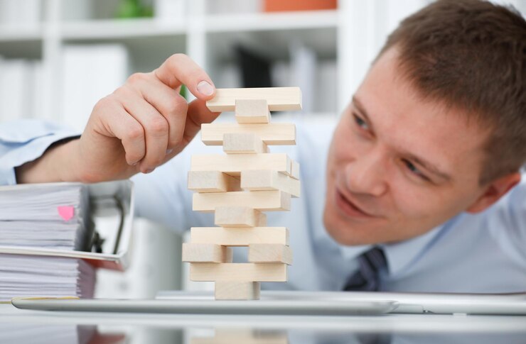 Foto el hombre de negocios juega en la estrategia mano reorganización de bloques de madera involucrados durante el descanso en el trabajo en la oficina sentado mesa juego pila diversión alegría concepto de pasatiempo