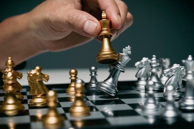 Hombre de negocios jugando tablero de ajedrez, competencia en los negocios, mano de hombre de negocios confiado usa pieza de ajedrez rey jugando para derrocar la estrategia comercial del equipo opuesto para ganar y éxito.