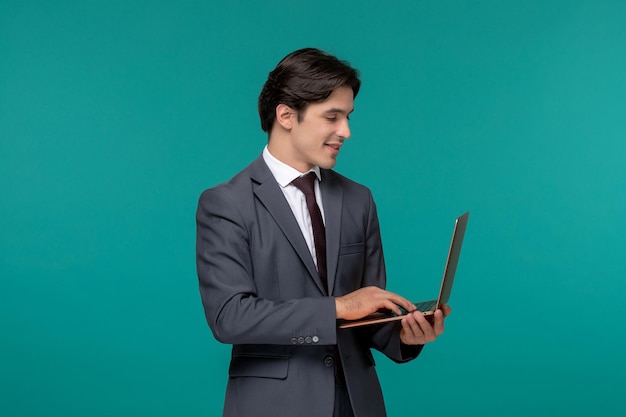 Hombre de negocios lindo chico guapo en traje de oficina gris y corbata trabajando en la computadora portátil