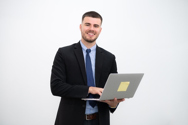 un, hombre de negocios, llevando, un, traje, y, sonriente, joven, guapo, mirar cámara del juez, con, computador portatil, en, fondo blanco