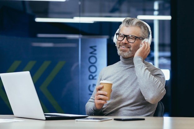 Hombre de negocios maduro con auriculares escuchando audiolibros, podcasts en línea y radio con hombre de música