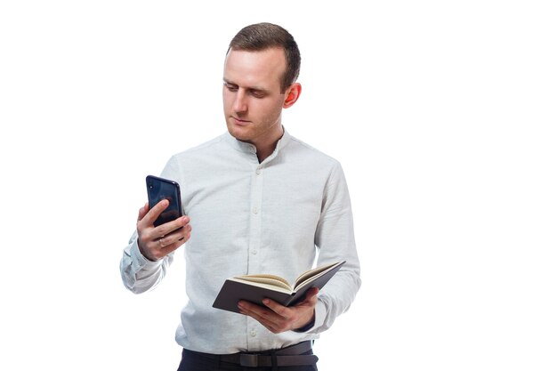 Hombre de negocios, maestro, mentor examina las entradas en su diario y habla por un teléfono celular. Aislado sobre fondo blanco