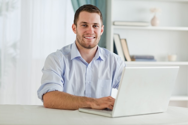 Hombre de negocios con mangas enrolladas en su computadora portátil en su homeoffice