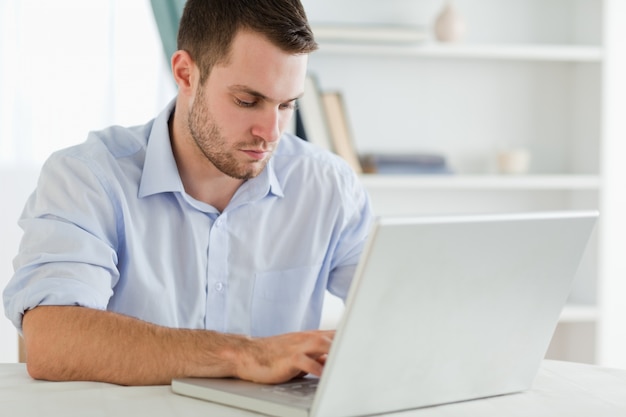 Hombre de negocios con mangas enrolladas en su homeoffice en su computadora portátil