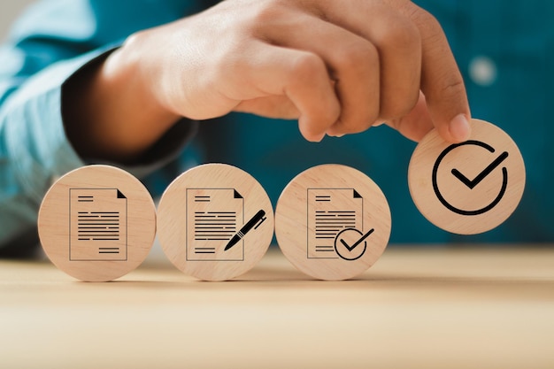hombre de negocios con la mano poniendo cubo de madera con iconos de documentos aprobados para el flujo de trabajo del proceso de negocio que ilustra la aprobación de la gestión y el concepto de aprobación del proyecto