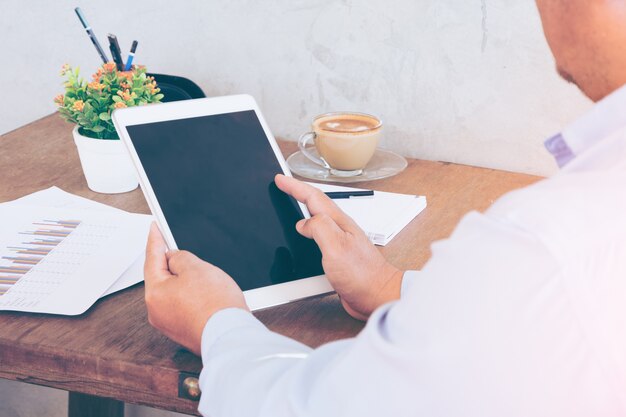 Hombre de negocios las manos sobre una mesa con tableta y una taza de café en una oficina