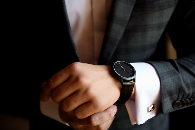 Hombre de negocios masculino se viste y ajusta su reloj, preparándose para una reunión.