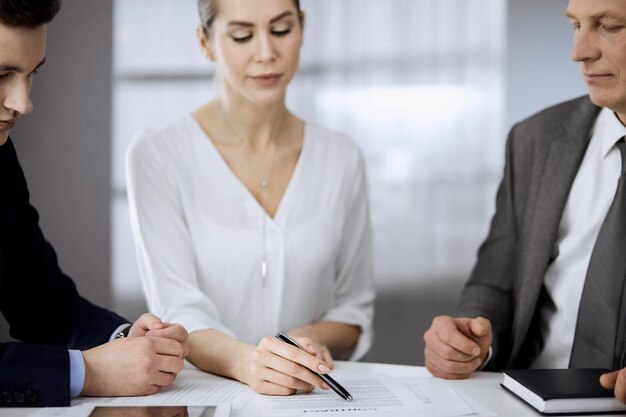 Un hombre de negocios mayor y un grupo de empresarios discutiendo el contrato en el cargo. Mujer y abogados trabajando juntos en la reunión. Trabajo en equipo y cooperación.