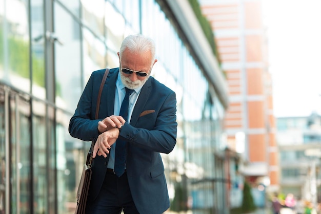 Hombre de negocios mayor que mira el reloj de pulsera