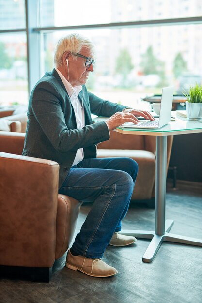 Hombre de negocios mayor que usa la computadora portátil en café