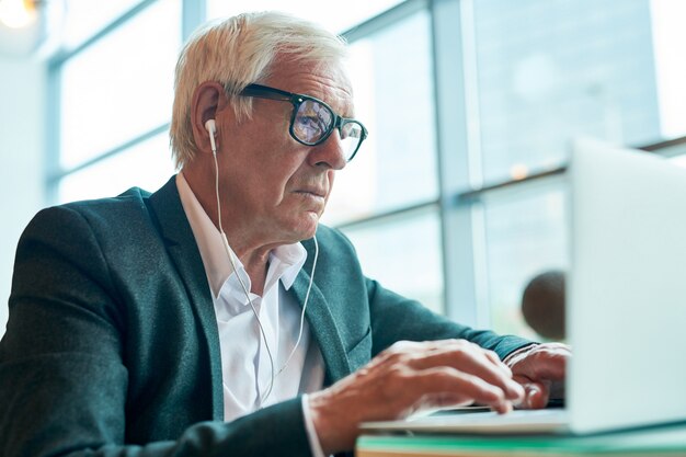 Hombre de negocios mayor que usa la computadora portátil en café