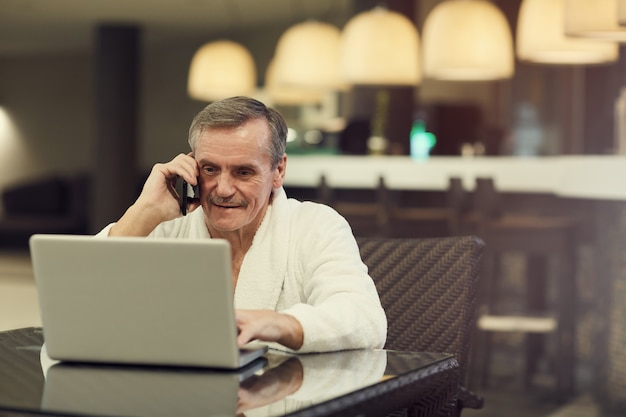 Hombre de negocios mayor que usa la computadora portátil en centro de BALNEARIO