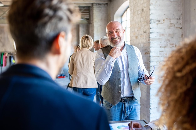 Hombre de negocios de mediana edad sonriendo mientras trabaja con colegas feliz grupo de personas creativas que trabajan en equipo de la industria de la moda y el diseño