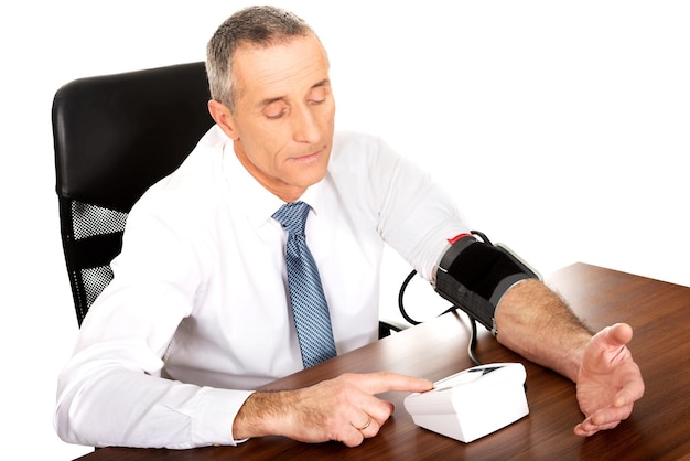 Un hombre de negocios midiendo la presión arterial en la oficina.