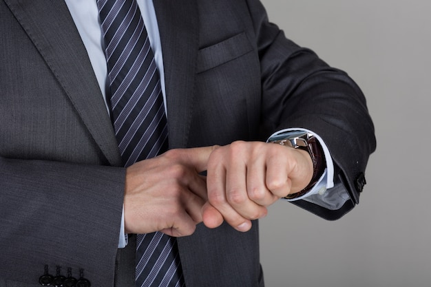 Hombre de negocios mira su reloj de pulsera comprobando la hora. Gestión del tiempo y concepto de fecha límite