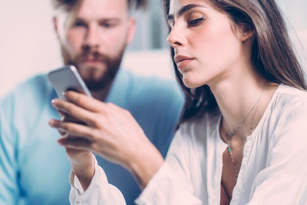 Un hombre de negocios mirando a una mujer usando el teléfono en la oficina.