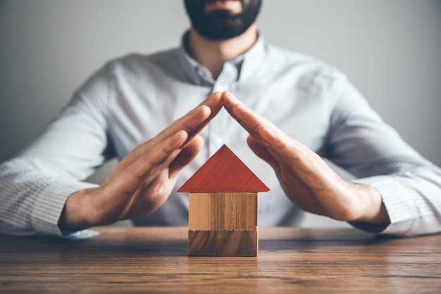 Hombre de negocios con modelo de casa en el escritorio.