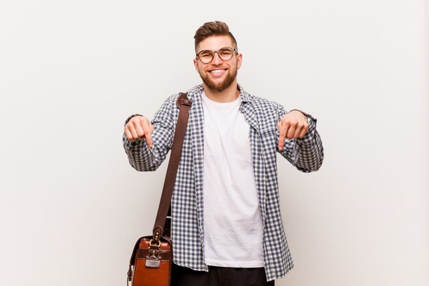 Hombre de negocios moderno joven apunta hacia abajo con los dedos, sentimiento positivo.