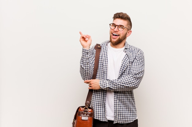 Hombre de negocios moderno joven que sonríe alegre que señala con el índice lejos.