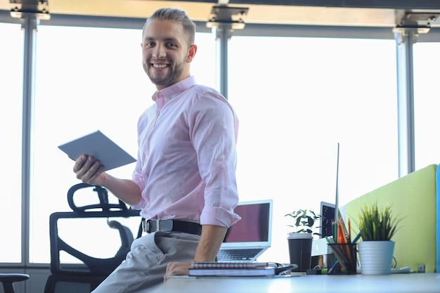 Hombre de negocios moderno joven que trabaja con tableta digital mientras está sentado en la oficina.