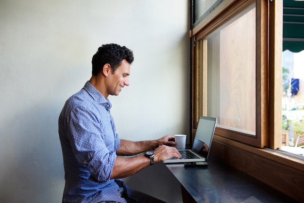 Hombre de negocios moderno que se sienta en el café con la computadora portátil