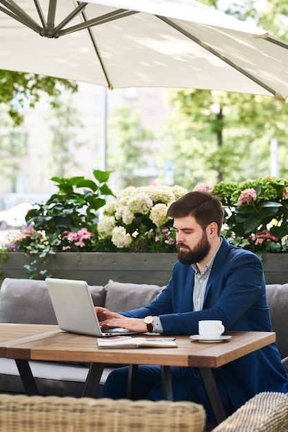 Hombre de negocios moderno que trabaja con la computadora portátil al aire libre