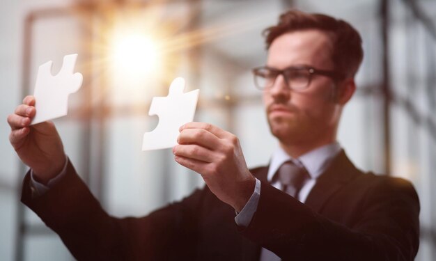 Foto el hombre de negocios muestra el rompecabezas blanco en la mano el concepto de estrategia empresarial.