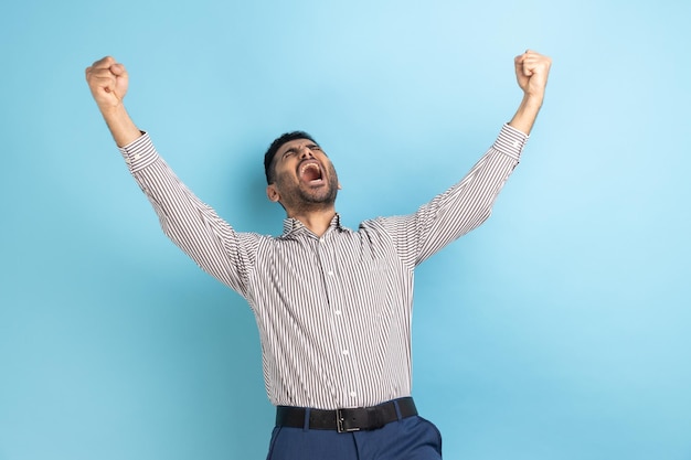 Un hombre de negocios muy contento expresando su gesto ganador con los puños levantados y gritando celebrando la victoria