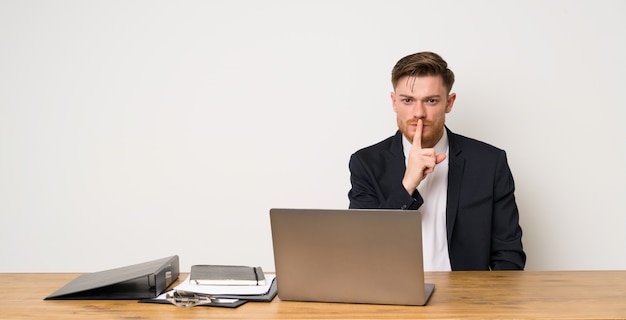 Hombre de negocios en una oficina que muestra un signo de silencio gesto poniendo el dedo en la boca