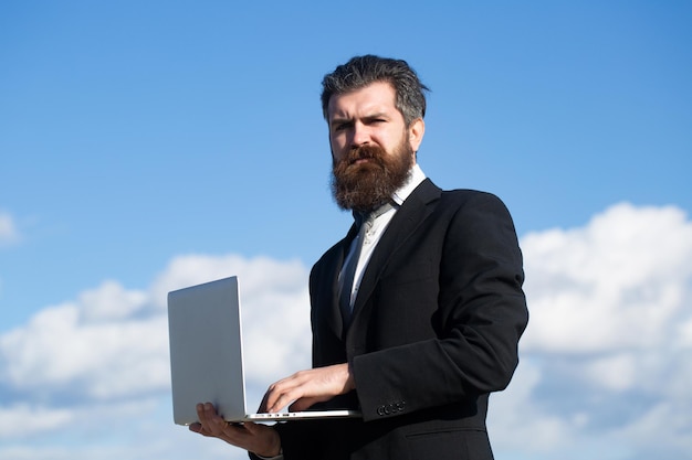 Hombre de negocios con ordenador portátil cielo al aire libre