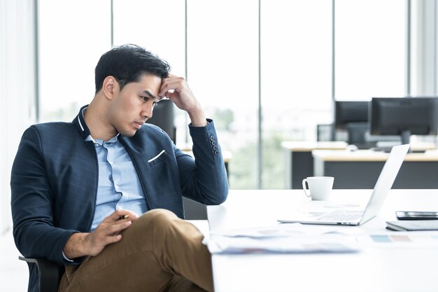 Hombre de negocios con ordenador portátil y dolor de cabeza