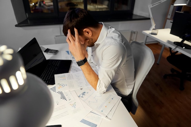 hombre de negocios con papeles trabajando en la oficina nocturna