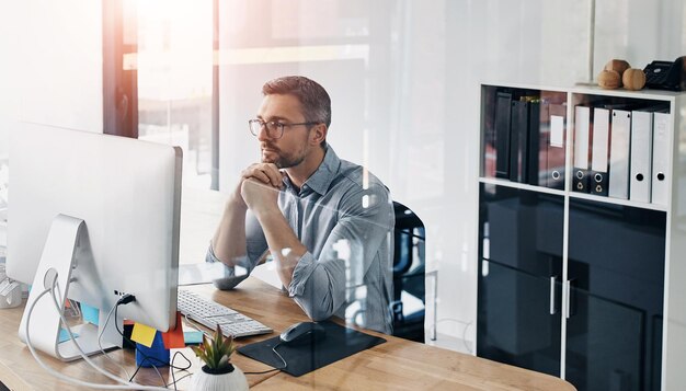 Hombre de negocios pensando e investigando en computadora para tecnología de la información o solución de programación Programador o desarrollador en línea con resolución de problemas lectura o ideas para actualización de software en la oficina