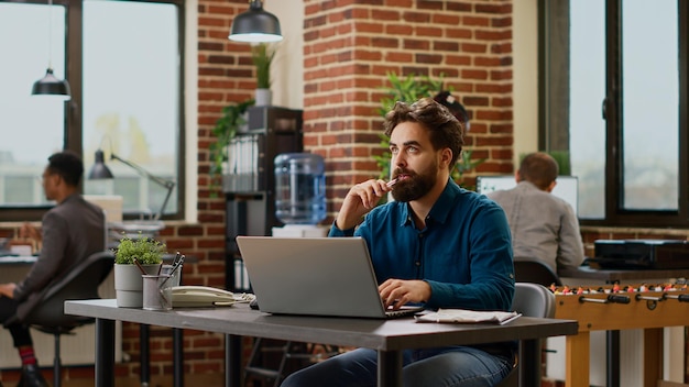 Un hombre de negocios pensativo que genera ideas para crear un informe en una computadora portátil, se siente pensativo y piensa en una buena decisión para crear una presentación. Trabajador estresado reflexionando sobre la solución de la empresa.