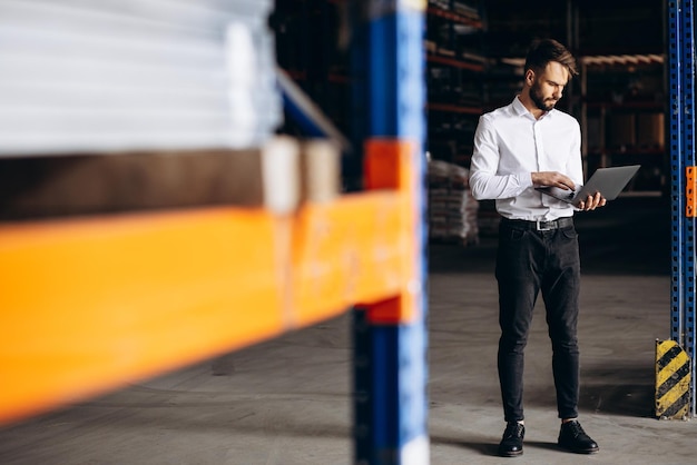 Foto hombre de negocios de pie en la fábrica y usando una computadora portátil