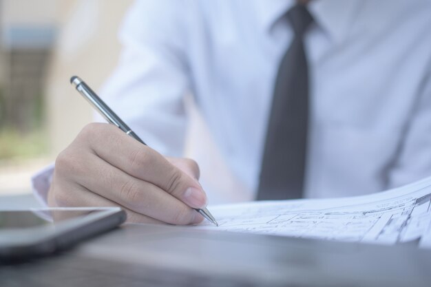 Hombre de negocios con pluma de escribir en el documento de trabajo de papel, cerrar la mano escribir papeleo
