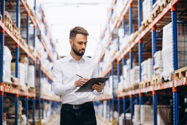 Foto hombre de negocios con portapapeles de pie en la fábrica.