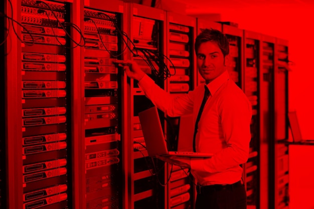 hombre de negocios con portátil en la sala de servidores de red