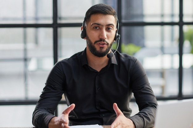 Hombre de negocios positivo hablando de auriculares en una computadora