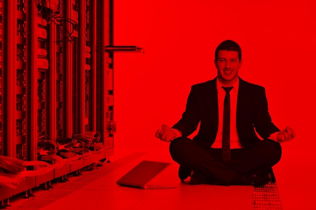 Foto hombre de negocios practica yoga en la sala de servidores de la red