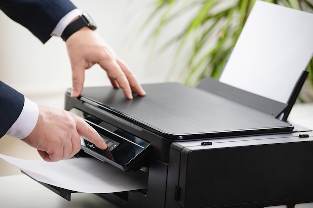 Foto el hombre de negocios presiona el botón en el panel del escáner de la impresora o en la copiadora láser en la oficina